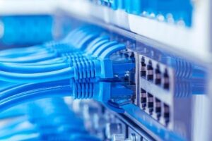 Network switch and cables, data center concept. Blue ethernet cables run into ports in switch.