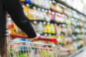 blurred photo of shopping cart being pushed down grocery aisle