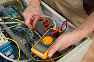 Fluke electrical voltage tester with no reading being used to measure output of wire or cable inside of cabinet.