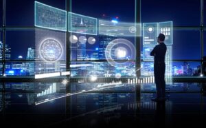 Business man standing in front of window with depiction of graphical communication display in front of him. Outside of window is night sky with illuminated city skyline.