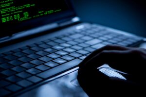 hand scrolling on laptop, green code visible