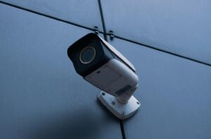 Mounted pointed security camera on wall surveying area.